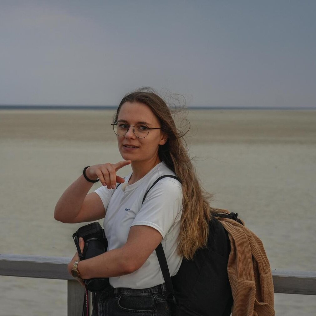 Marina steht auf der Seebrücke und zeigt auf die Dünen