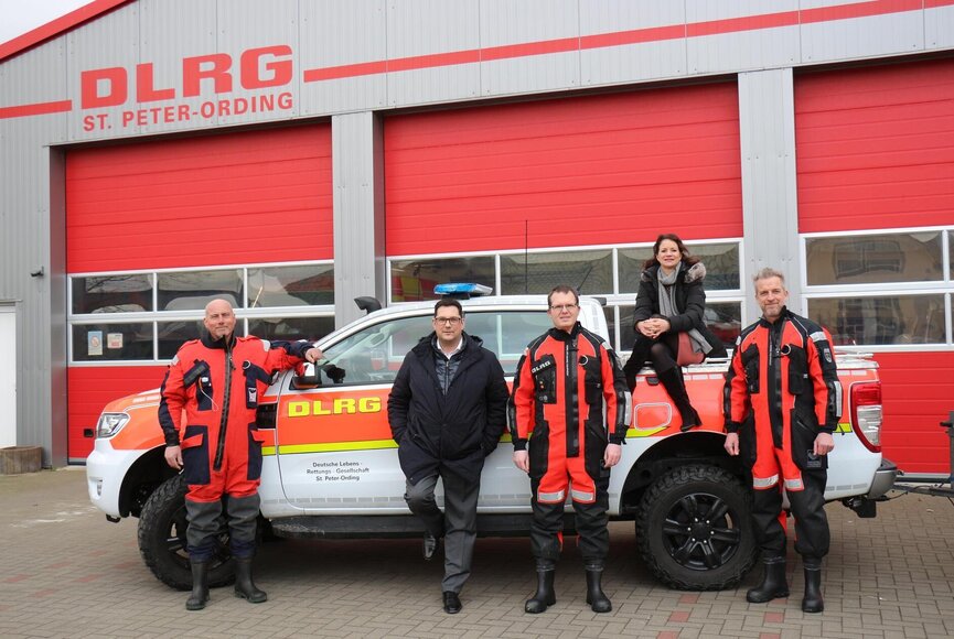 Team der DLRG vor dem DLRG Lagerhaus mit Einsatzfahrzeug