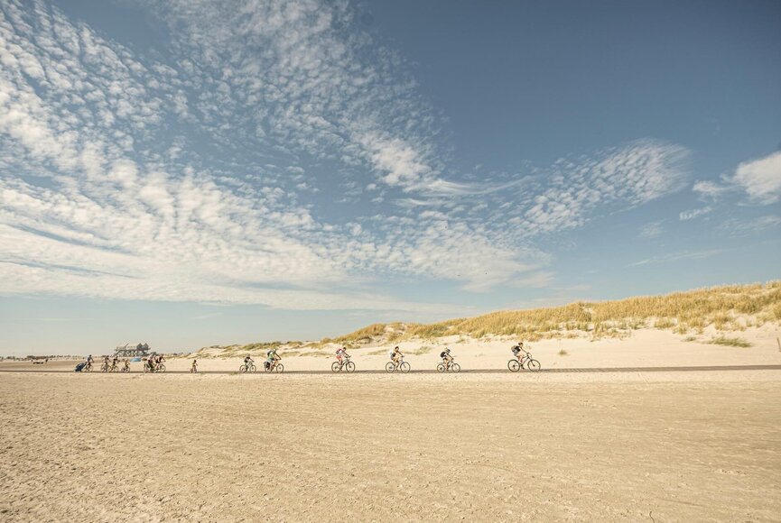 Gruppe von Radfahrern auf dem Holzsteg am Strand