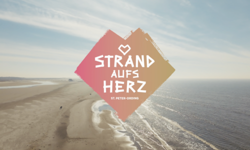 Drohnenaufnahme vom Strand mit Strand aufs Herz Logo