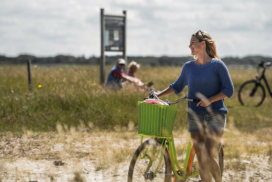 Frau schiebt Fahrrad durch die Salzwiesen