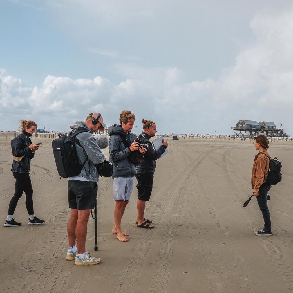 Marina und die Filmagentur am Strand, Strandkörbe und Pfahlbauten im Hintergrund