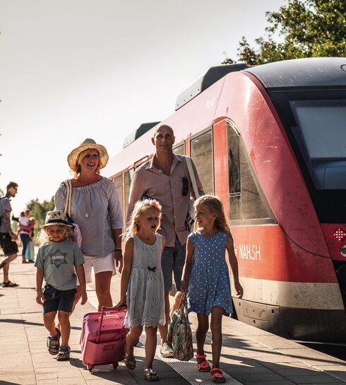 Familie mit Gepäck bei der Ankunft am Bahngleis in St. Peter-Ording