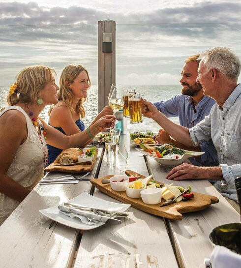 Freunde stoßen auf der Dachterrasse eines Pfahlbaus gemeinsam an