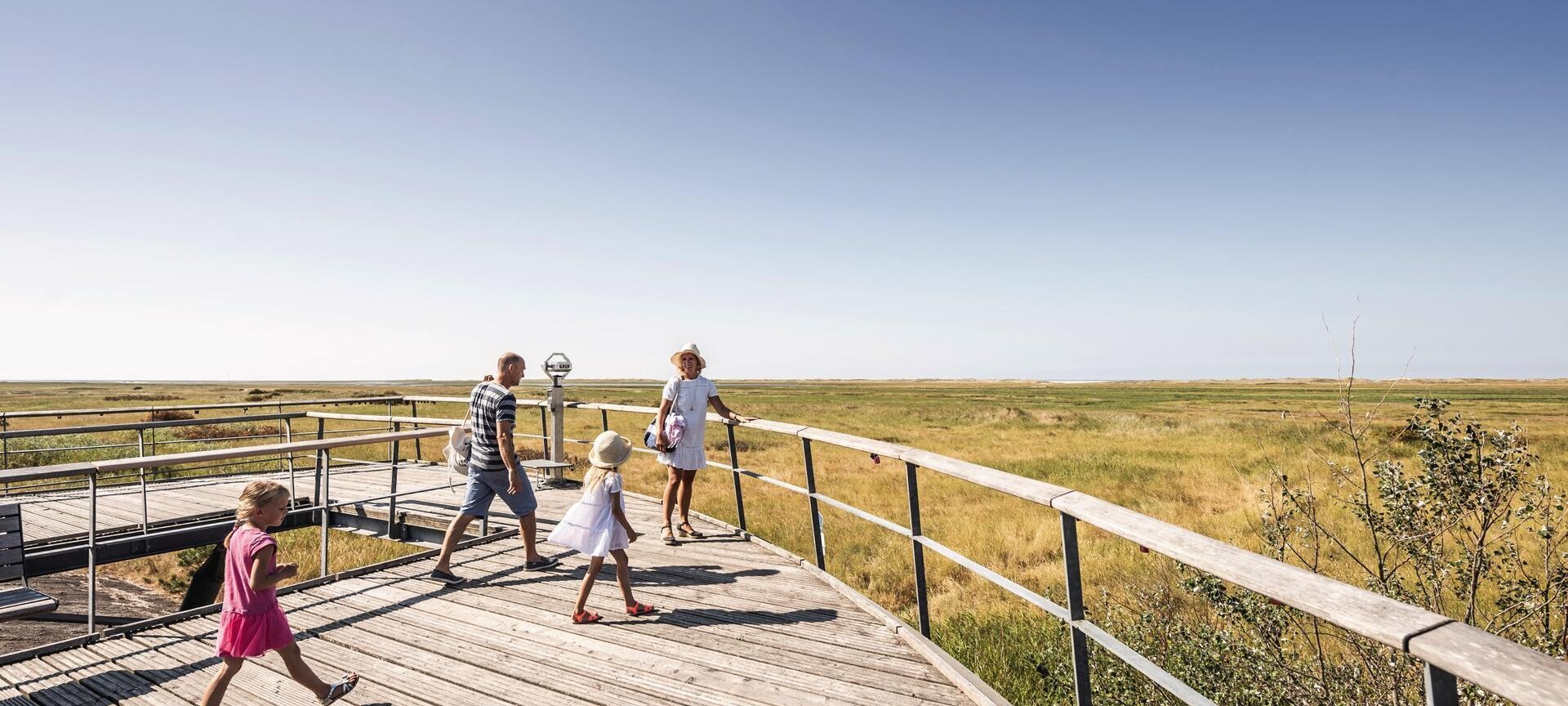 Familie auf einer Aussichtsplattform mit Blick auf die Salzwiesen