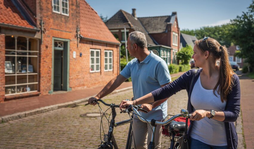 Paar mit Fahrrädern vor traditionellen Giebelhäusern