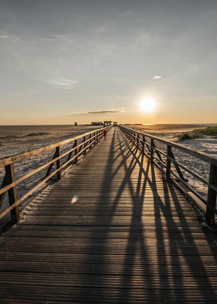 Seebrücke in Richtung Strand bei Sonnenuntergang
