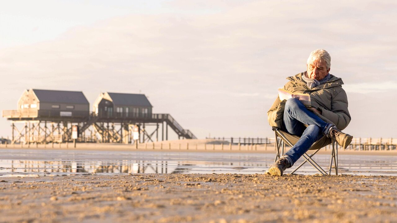 Mann sitzt mit Strandstuhl am Strand und liest entspannt in einem Buch, YouTube-Video-Thumbnail