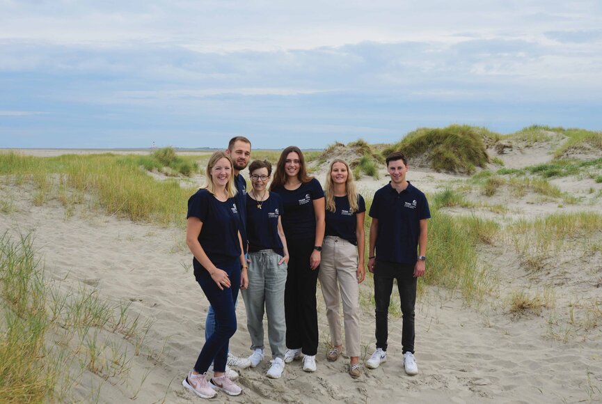 Group photo of tourist information staff on the beach among the dunes. 