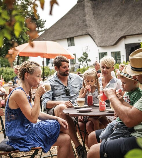 Familie sitzt im Hof eines Hofcafés